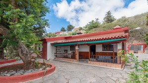 A traditional house with a tiled roof, a porch with a railing, and a stone-paved courtyard.