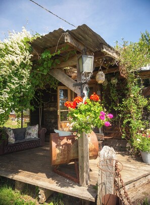 A rustic wooden cabin with a porch, a vintage lantern, and a flower vase. - Little Lodge Glamping (Diss)
