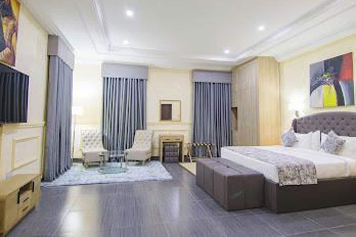Ein modernes Hotelzimmer mit einem großen Bett, einem Schreibtisch und einem Sessel. Ein Flachbildfernseher ist an der Wand angebracht.