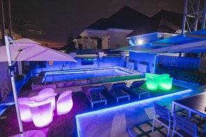 An outdoor pool area with lounge chairs, a table, and a large umbrella. - BON hotel Asokoro Residence (Abuja)