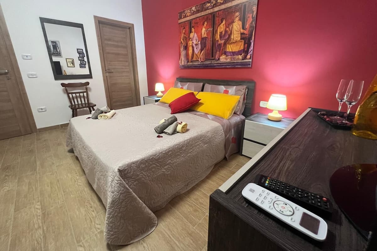 Een hotelkamer met een bed, nachtkastjes, een schilderij aan de muur en een televisie.