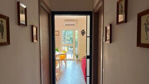 Un couloir orné de tableaux encadrés le long des murs, qui mène à un espace repas comprenant une table et des chaises.