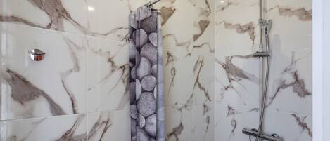 Ducha con pared de mármol y cortina de piedra.