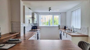 Eine moderne Küche mit Holzarbeitsplatte, integriertem Backofen und einem Fenster mit Jalousien.