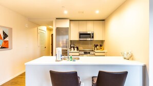 Une cuisine moderne dotée d’un îlot central, d’appareils électroménagers en acier inoxydable et d’un design minimaliste.