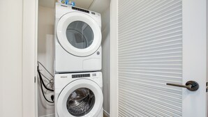 A compact, white, two-door laundry room with a modern design, featuring a Whirlpool brand washer and dryer. - Luxury Apt in Seaport with Gym and Pool (Boston)