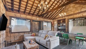 A rustic interior with stone walls, a wooden ceiling, a sofa, a coffee table, and a bookshelf. - "Casa Rural La Venta" with Sea View, Private Pool & Wi-Fi (Las Vegas)