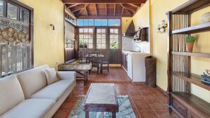 A cozy living area with a sofa, dining table, and kitchen area with a tiled floor and wooden ceiling. - "Casa Rural La Venta" with Sea View, Private Pool & Wi-Fi (Las Vegas)