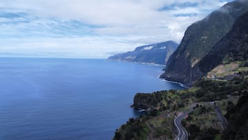 A coastal road winding through a mountainous area with a view of the ocean and a distant coastline.