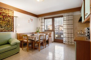 Ein Essbereich mit Tisch, Stühlen, einer Couch und einem Fenster mit Vorhängen.