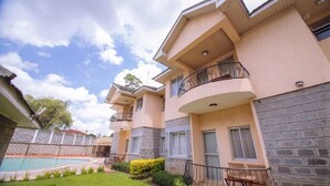 A multi-story residential building with balconies, a swimming pool, and a well-maintained garden.