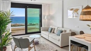 A modern living room with a sofa, a dining table, and a view of the ocean.