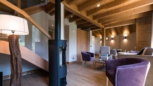 A modern interior with a wooden ceiling, a black fireplace, and purple chairs. - Praz-sur-Arly | Sleeps 6 | Vues imprenables (Praz-sur-Arly)