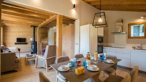 A modern interior with a dining area, kitchen, and living space. - Praz-sur-Arly | Sleeps 6 | Vues imprenables (Praz-sur-Arly)