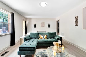A modern living room with a sectional sofa, a round coffee table, and a view of the outdoors. - Serenity in the Scenic City (Chattanooga)