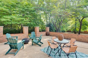 An outdoor patio with green Adirondack chairs, wicker table, and a round table with chairs.