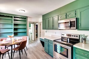 A kitchen with teal cabinets, a stainless steel oven, and a microwave.