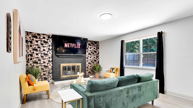 Ein Wohnzimmer mit Kamin, einem grünen Sofa, einem gelben Sessel und einem Couchtisch.