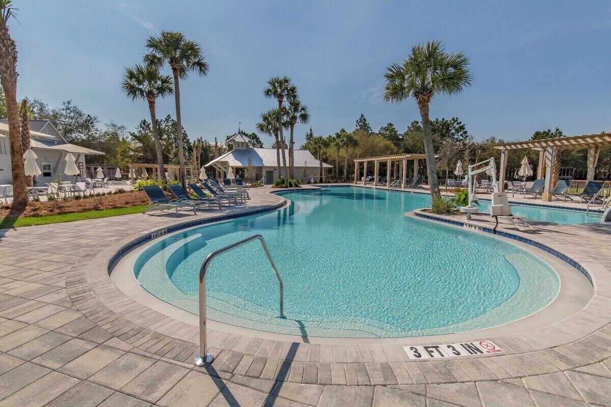 A swimming pool with lounge chairs and palm trees.