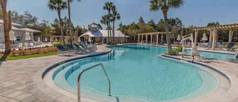 A swimming pool with lounge chairs and palm trees.