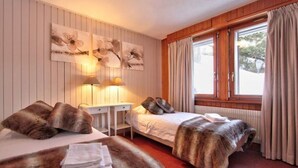 Ein Hotelzimmer mit zwei Betten, einem Schreibtisch und einem fenster mit Vorhängen.