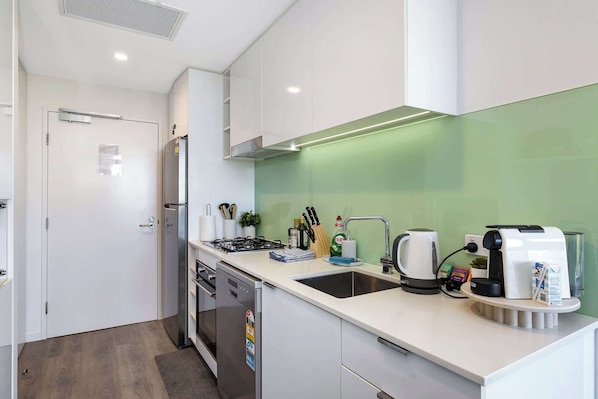 A modern kitchen with a gas stove, sink, and coffee maker.