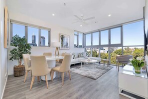Ein modernes Wohnzimmer mit Essbereich, großen Fenstern und Blick auf die Stadt.