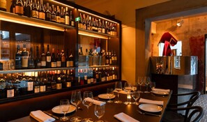 A bar area with shelves of wine bottles, glasses, and neatly set dining tables. - 2BR South Brisbane | Free Parking + Walk to QPAC (South Brisbane)