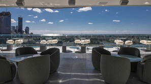 Eine Dachterrasse mit moderner Sitzgelegenheit, Glasgeländer und Blick auf den Stadtgürtel.
