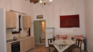 A kitchen with wooden cabinets, a dining table with chairs, and a chandelier. - Holiday Home 'House For Rent In Apostolous' with Mountain View, Private Garden and Wi-Fi (Iraklio)
