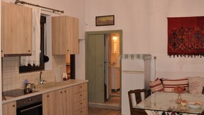 A kitchen with wooden cabinets, a chandelier, and a dining area with a table and chairs. - Holiday Home 'House For Rent In Apostolous' with Mountain View, Private Garden and Wi-Fi (Iraklio)