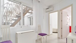 A room with a radiator, a chair with a purple cushion, a white radiator, and a door leading to another room.