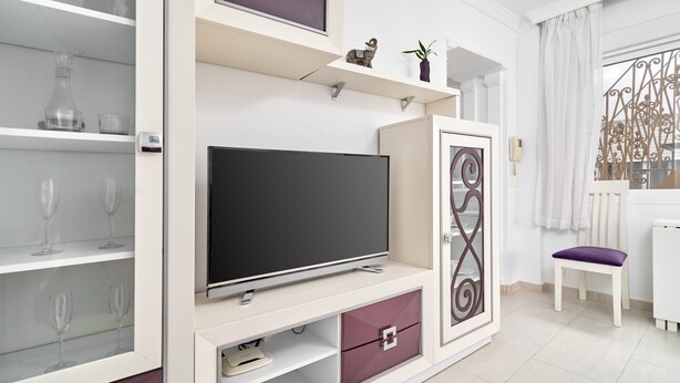 A modern living room with a flat-screen TV, built-in shelves, and a decorative metal partition.
