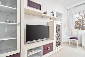 A modern living room with a flat-screen TV, built-in shelves, and a decorative metal partition.