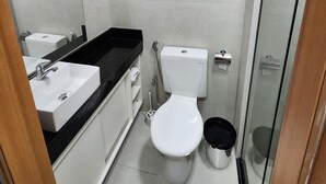 A bathroom with a white toilet, a sink, and a shower area. - Flat Ofurô 15 VP by La Playa (Ipojuca)