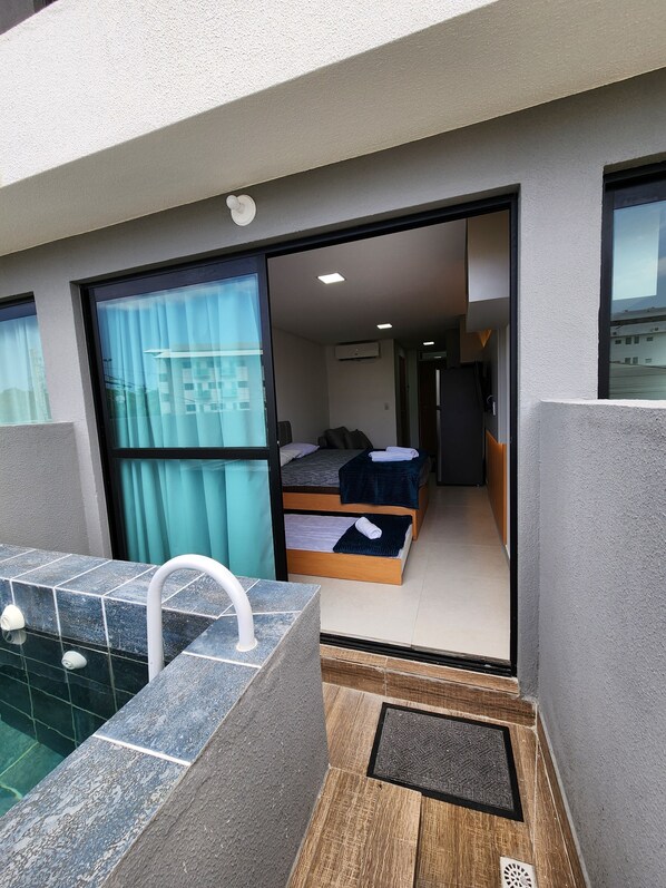 A modern hotel room with a balcony, a small pool, and a view of the cityscape. - Flat Ofurô 15 VP by La Playa (Ipojuca)