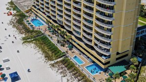 A multi-story hotel with balconies, a pool, and beach access.