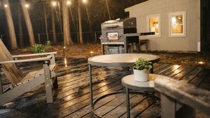Une terrasse extérieure avec un barbecue, des chaises et une table.
