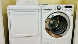 A compact laundry room with a front-loading washer and a top-loading dryer. - Spacious Raleigh Retreat | Near Downtown + I-440 (Raleigh)