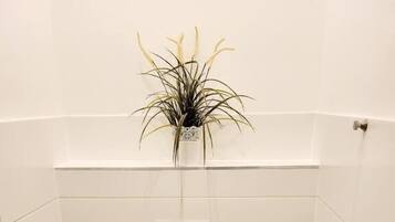 Un bagno piccolo e bianco con servizi igienici, lavandino e una pianta in vaso appesa al muro.