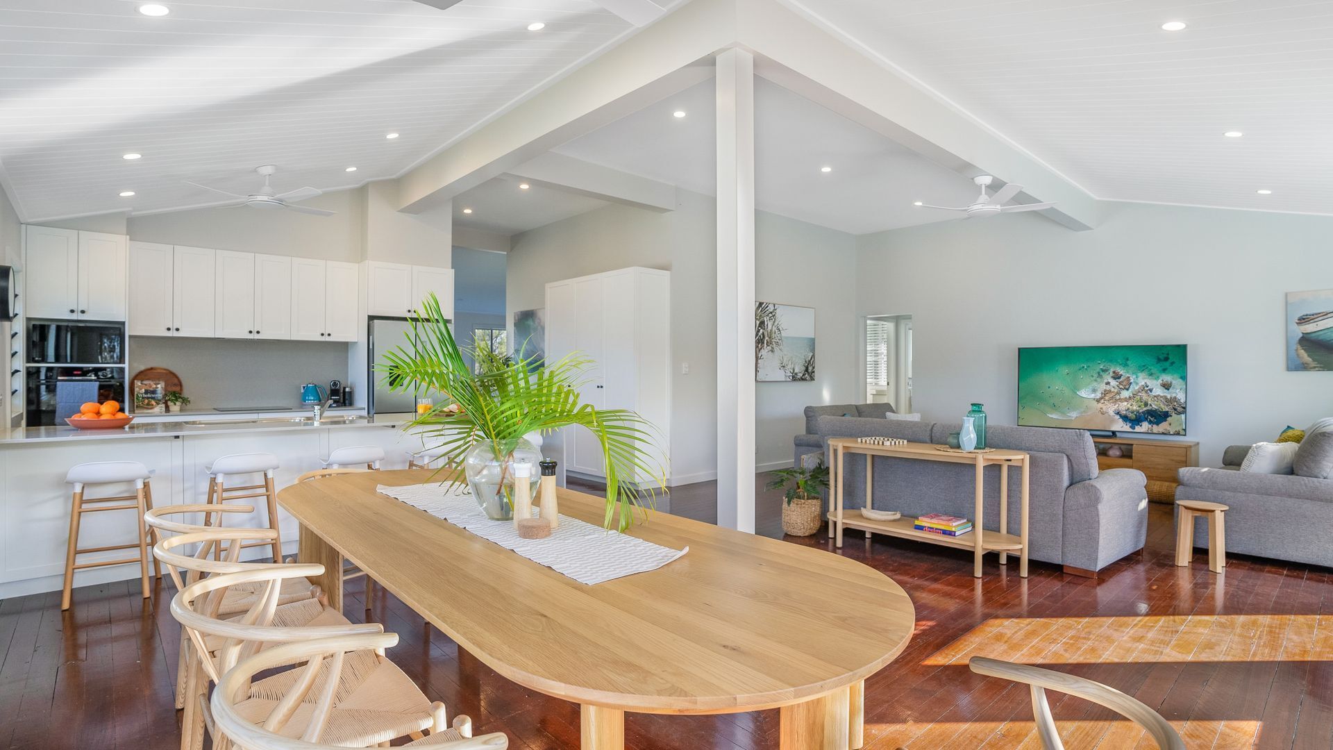 A modern living space with a wooden dining table, white cabinetry, and a grey sofa.
