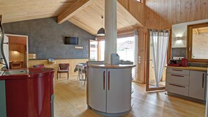 Un'ampia cucina con travi in legno, un'isola centrale e un'area pranzo con sedie.