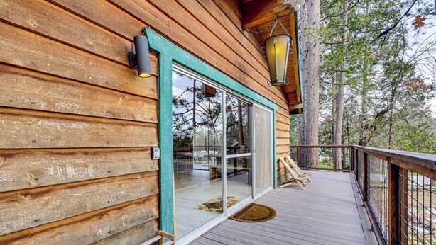 A wooden cabin with a deck, large windows, and a hanging lantern. - Peaceful Wooden Cabin, 2 Mi to Bass Lake! (Oakhurst)
