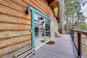 Una baita di legno con veranda, ampie finestre e una lanterna appesa.