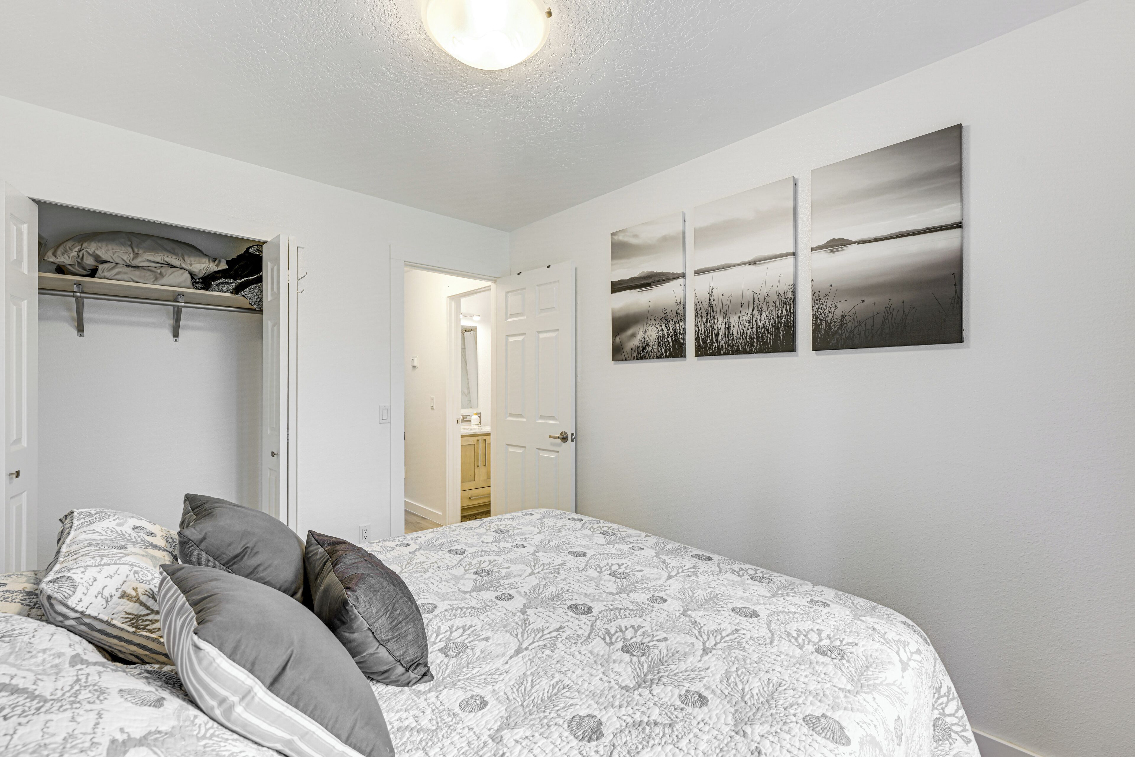 A bedroom with a bed, a closet with hanging storage, and a door leading to a bathroom.