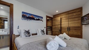 Ein modernes Schlafzimmer mit einem großen Bett, einem Holzschrank und einem Gemälde einer Berglandschaft.