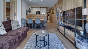 Ein modernes Wohnzimmer mit einem braunen Sofa, einem runden Couchtisch und einem gemusterten Teppich.
