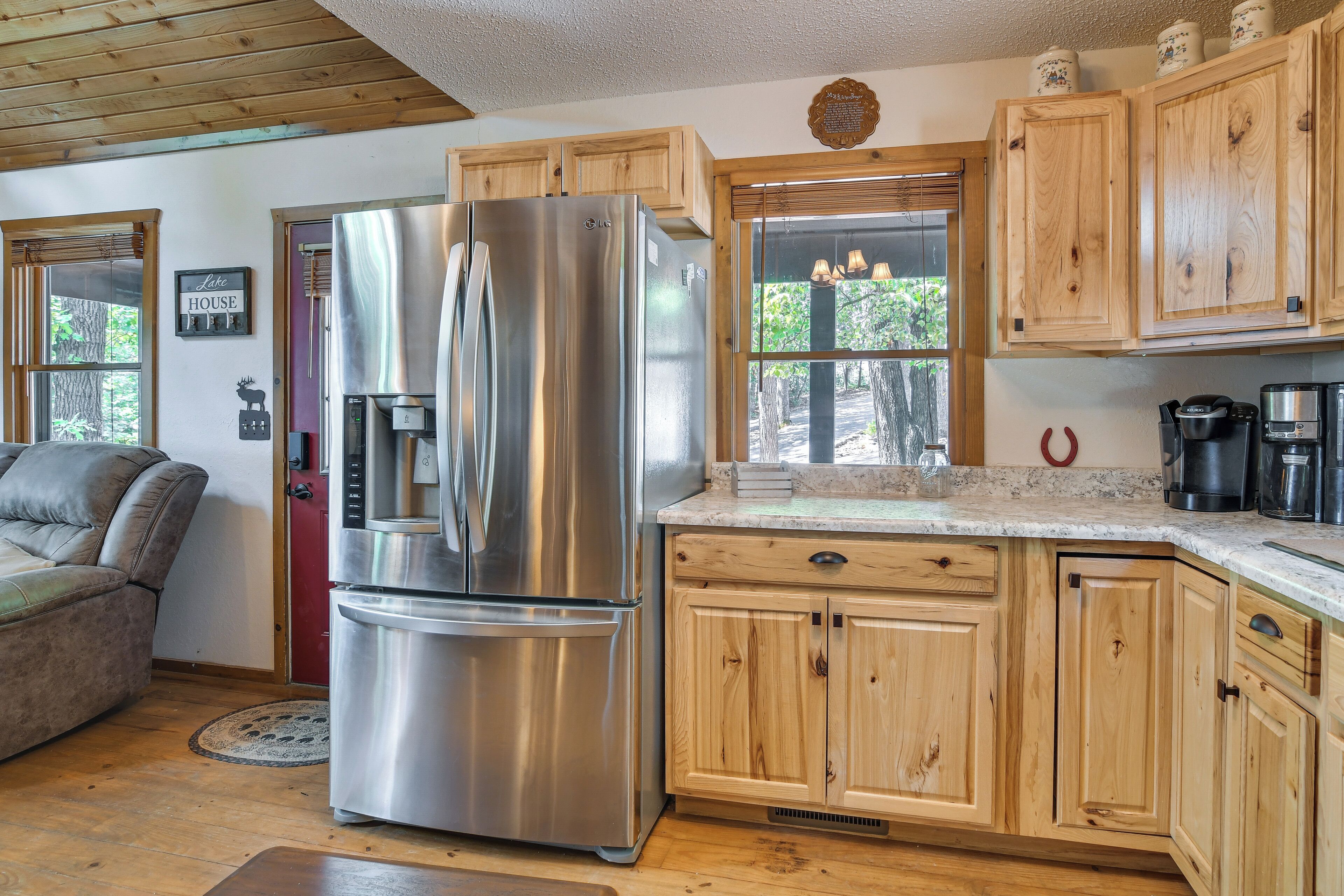 Una cocina con armarios de madera, un refrigerador de acero inoxidable, una cafetera y vistas al exterior.