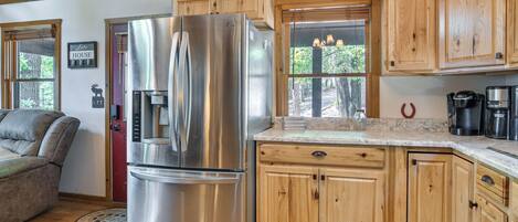 Una cocina con armarios de madera, un refrigerador de acero inoxidable, una cafetera y vistas al exterior.