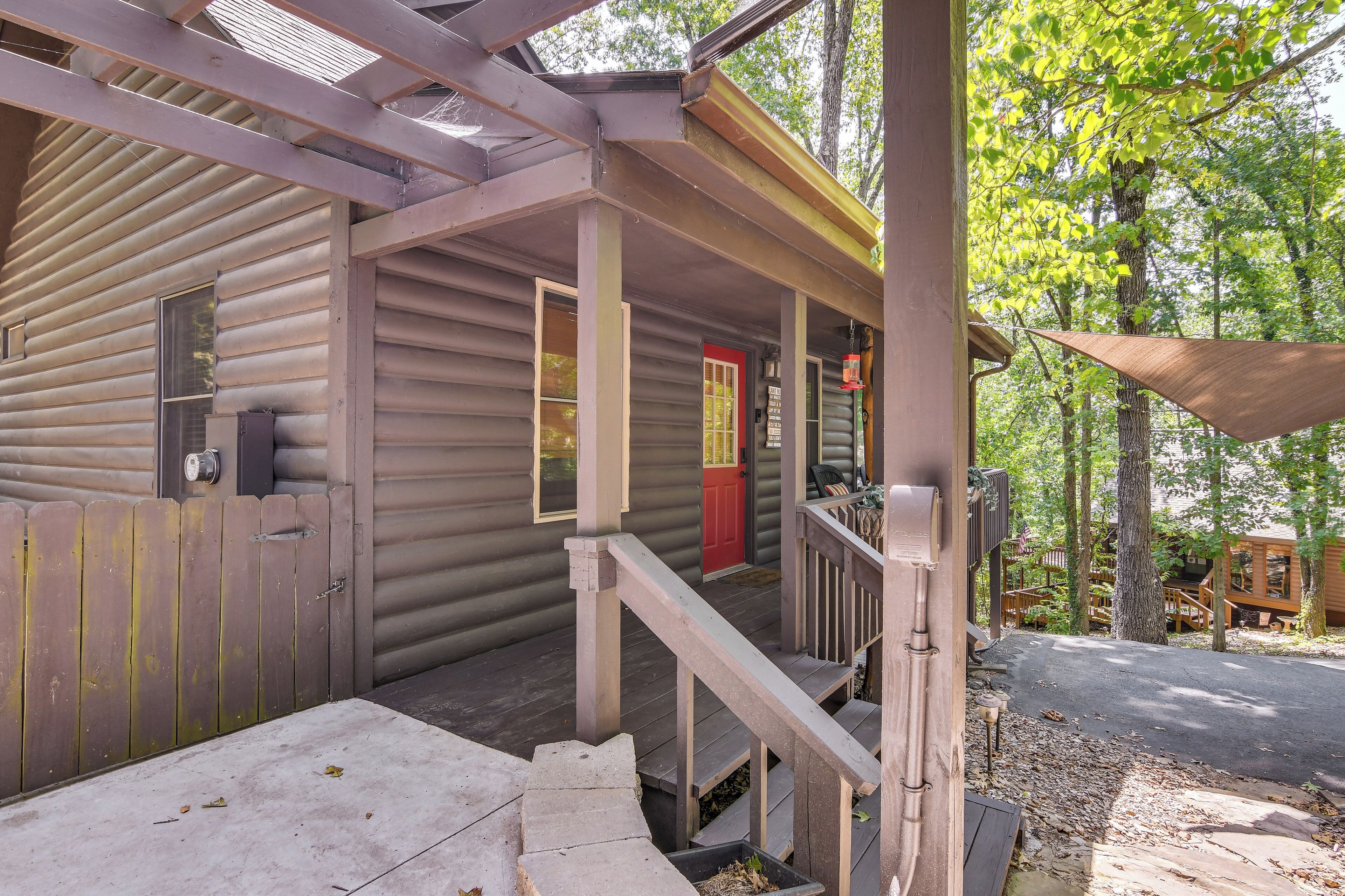 Eine Holzhütte mit Veranda, einer roten Tür und einer Treppe, die zum Eingang führt.